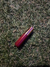 a red lipstick laying on the grass